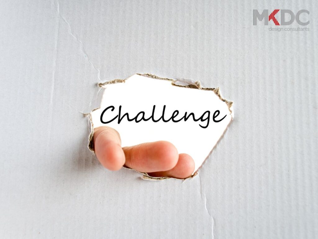 A torn paper revealing the word "Challenge" with a finger emerging from the hole.
