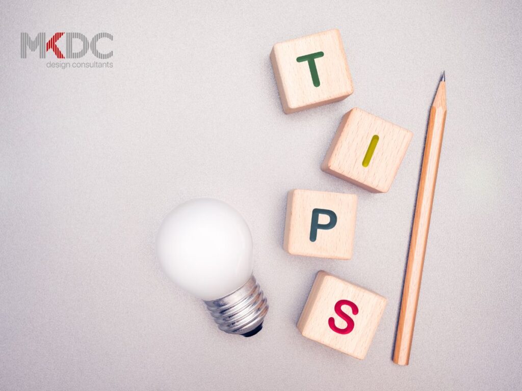 Wooden blocks spelling "TIPS" alongside a pencil and light bulb on a gray surface.
